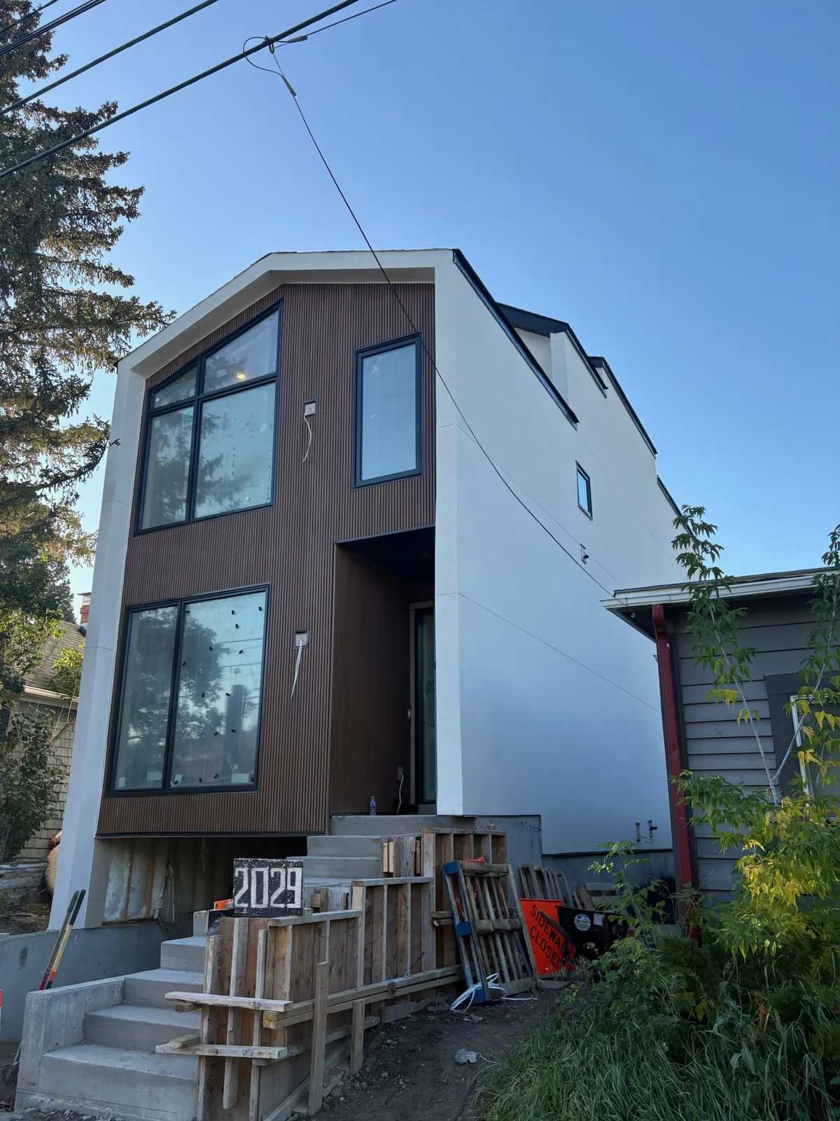 Modern custom home with wood-look siding, white stucco and large black-framed windows