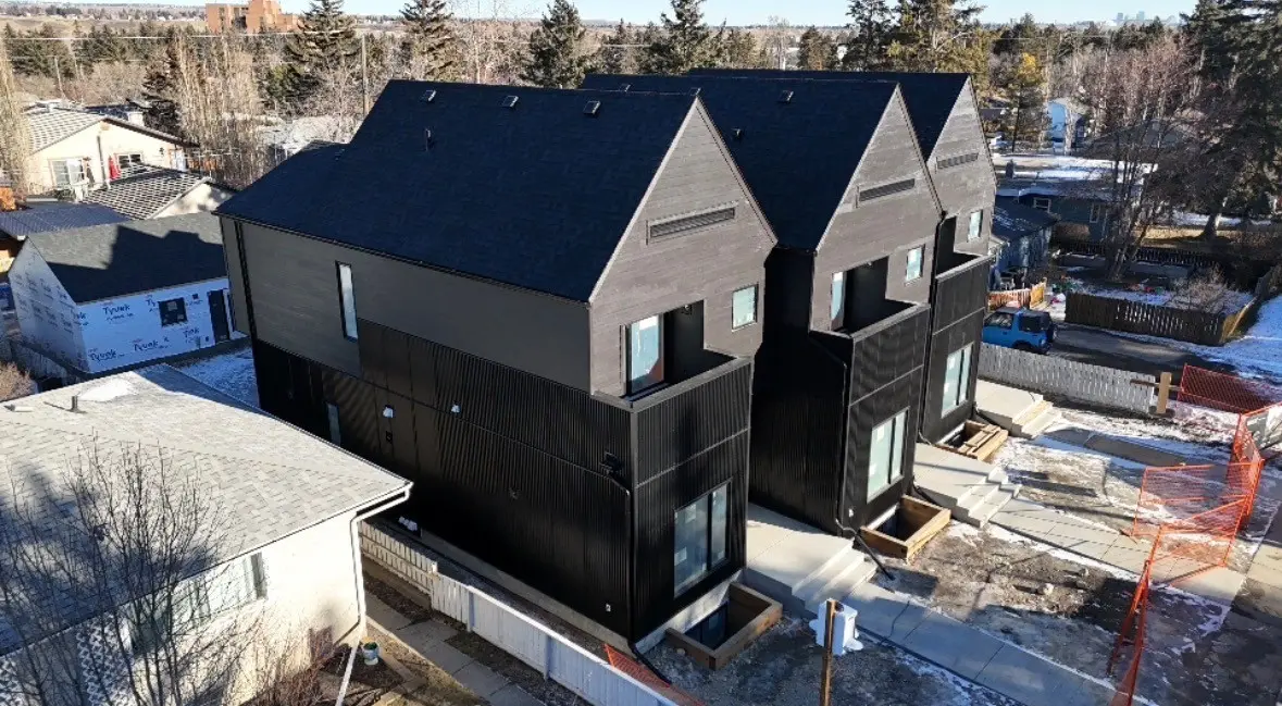 Aerial view of custom townhomes with dark siding and new shingle roofs