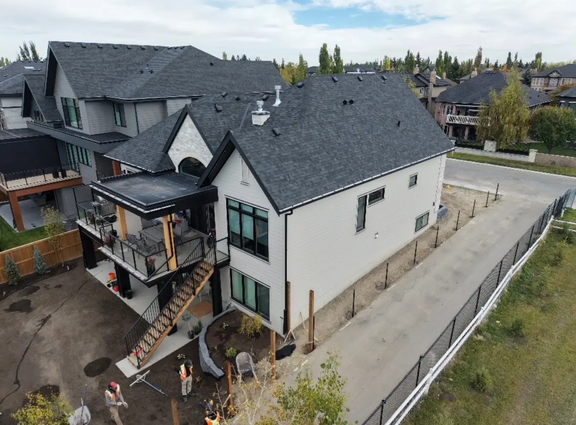 Aerial view of a large custom home with stucco, black windows and a new shingle roof