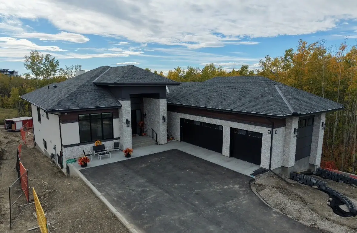 Custom home with stone accents, dark garage doors and a new shingle roof