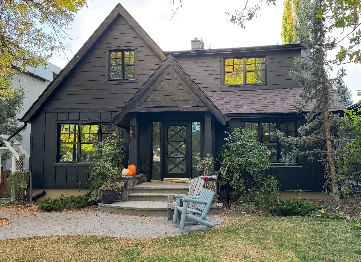 White stucco home with stone base, dark trim and black windows