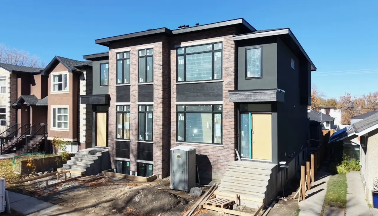 Brick and dark stucco duplex with black windows and new front steps