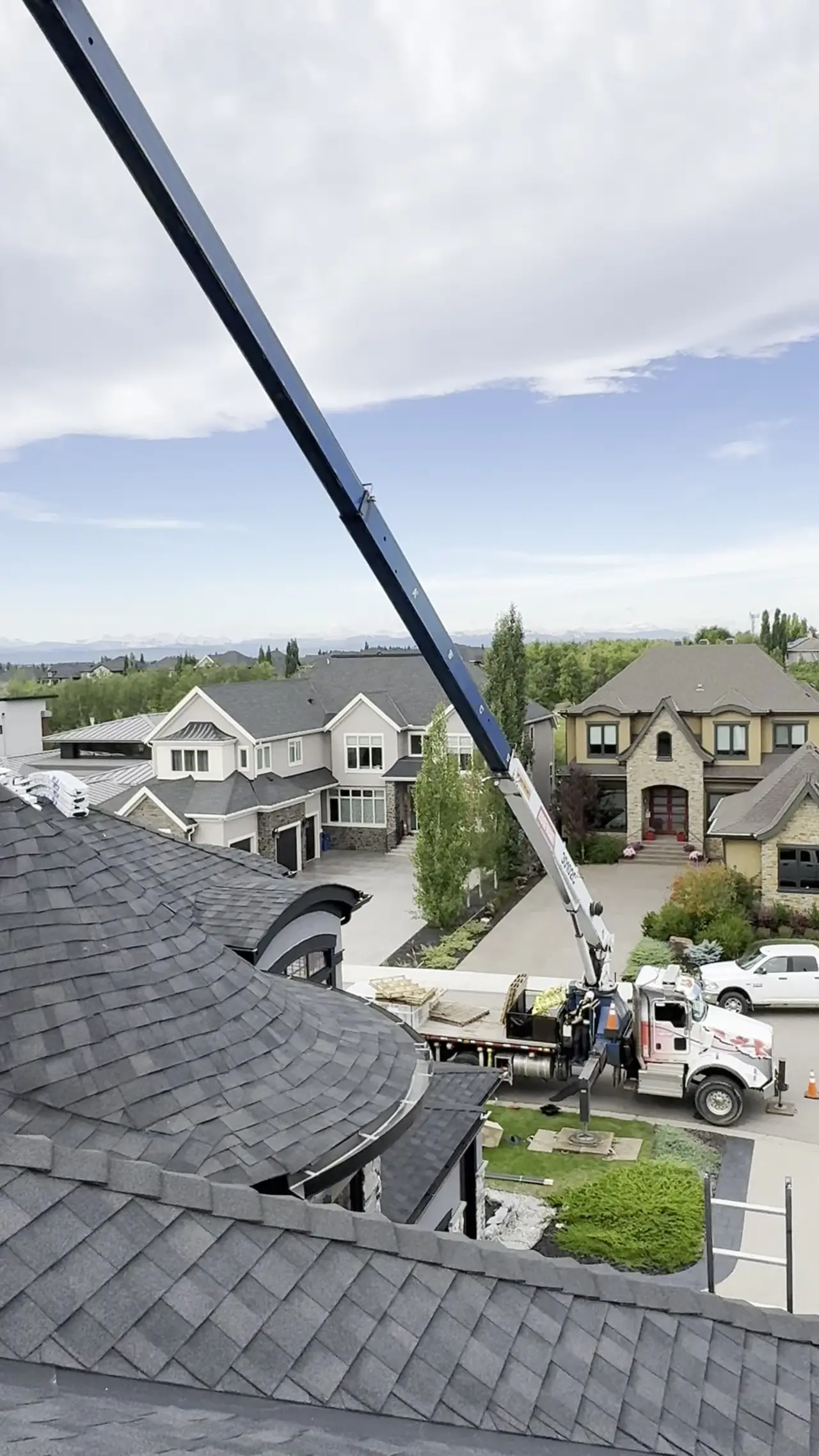 Video from the roof as a crane lifts shingle pallets up onto a large estate home