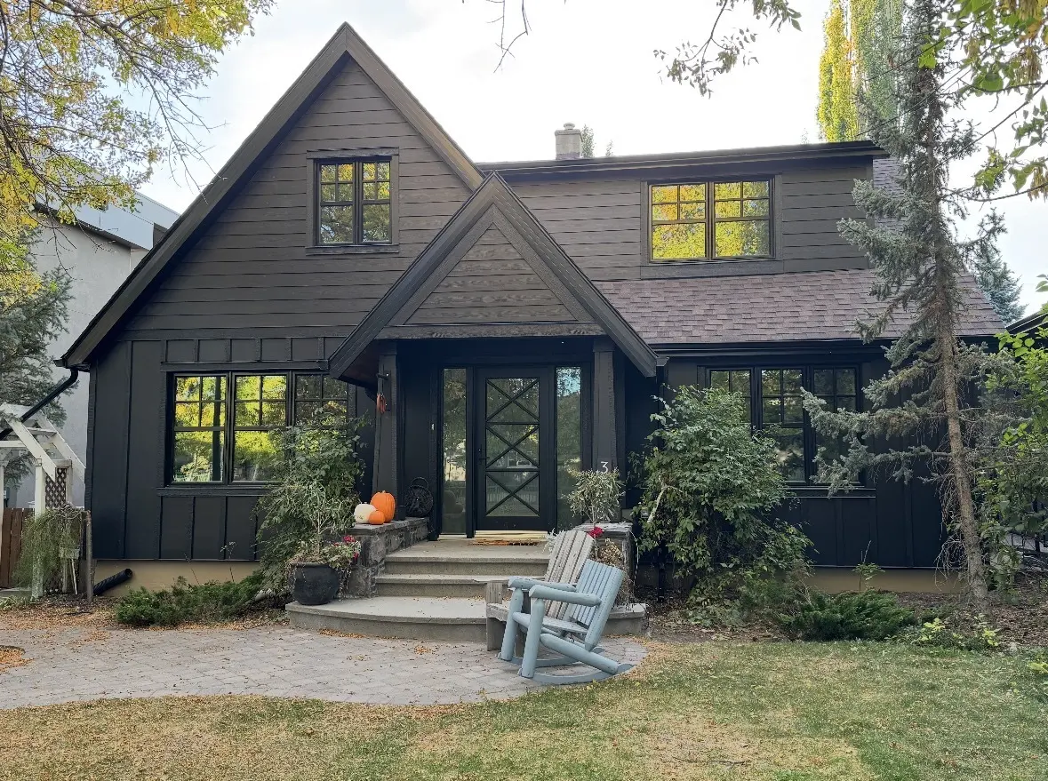 Two storey home finished in dark James Hardie siding with board and batten gables and black framed windows