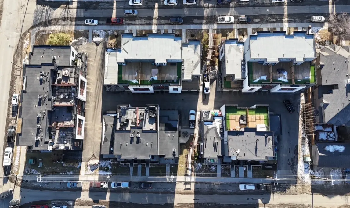 Top-down aerial view of a townhome complex with flat roofs and rooftop decks