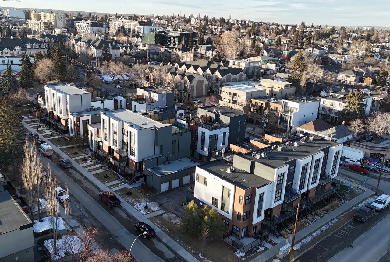 Aerial view of a modern white, grey and brick townhome complex on a Calgary street