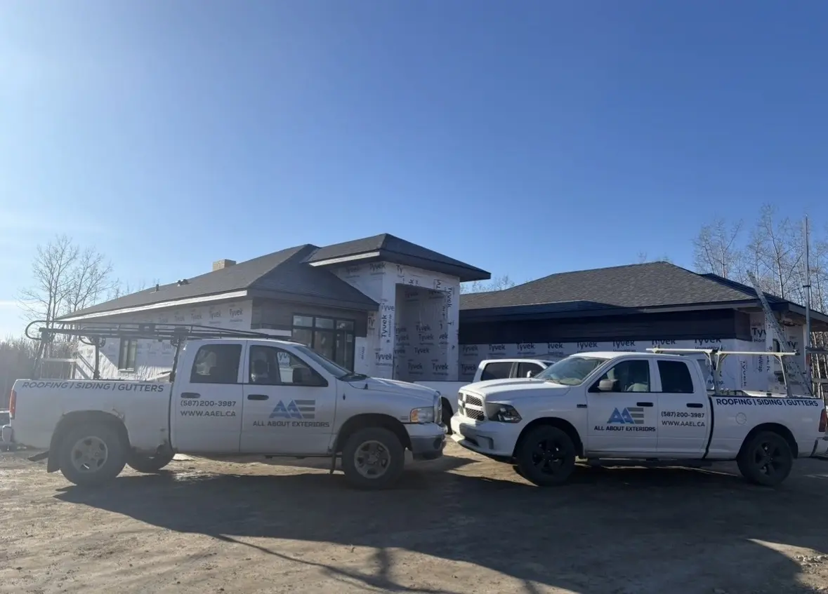 Two All About Exteriors trucks at a new home wrapped in weather barrier, ready for siding