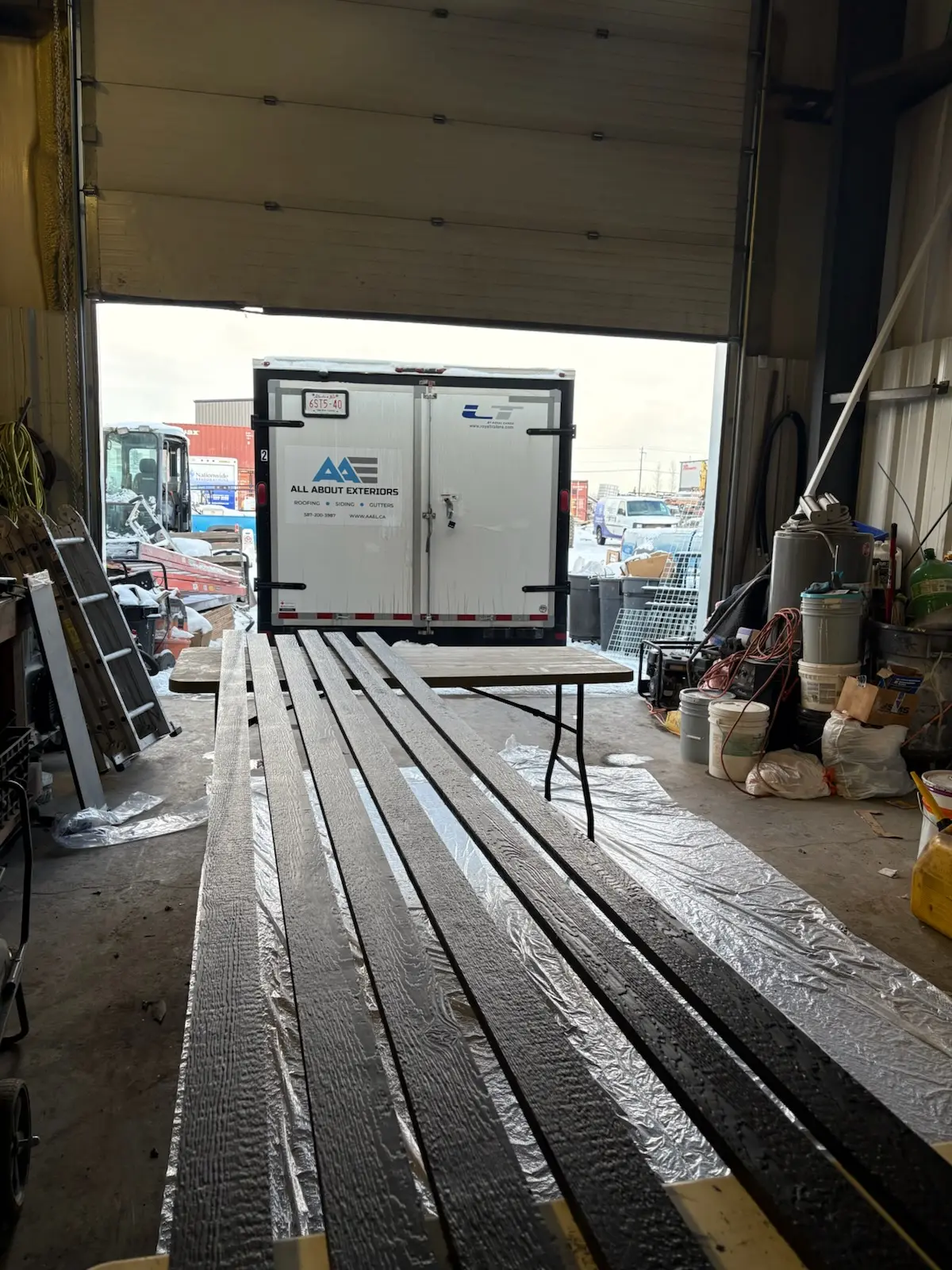 Freshly painted dark wood grain trim boards drying in the All About Exteriors shop