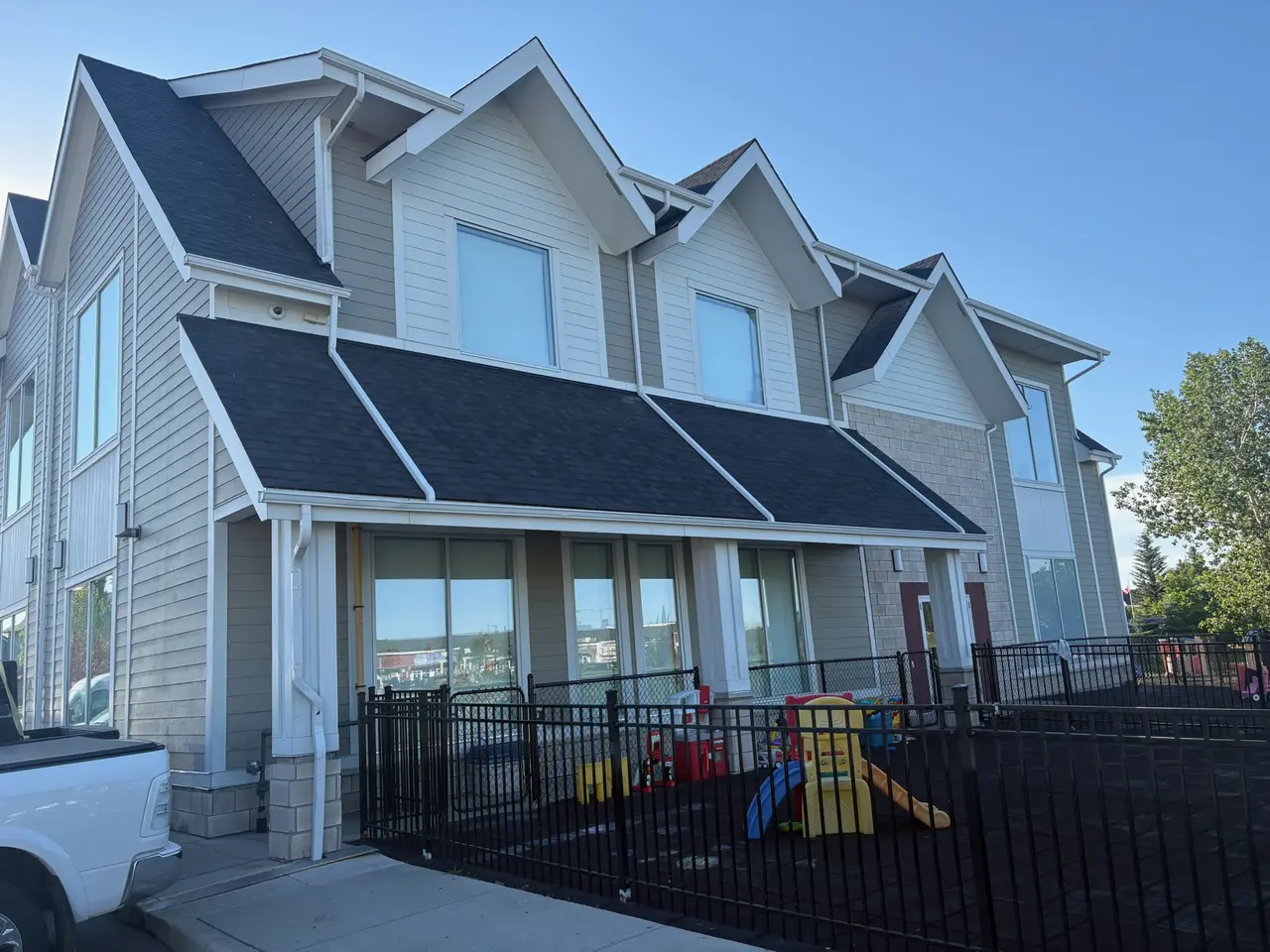 Two storey townhome building with grey siding and a dark shingle roof over the front porch
