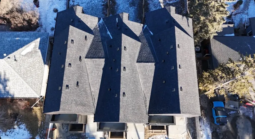 Aerial view of a new dark grey shingle roof on a townhome with several hips