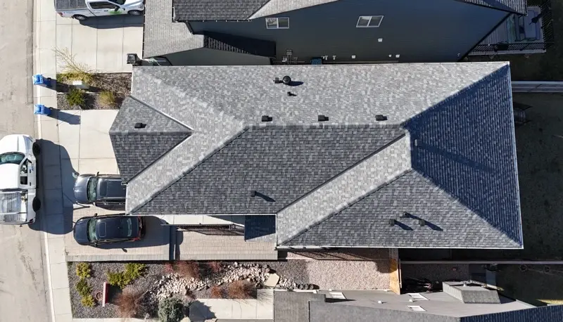 Aerial view of a new grey shingle roof on a home with a driveway