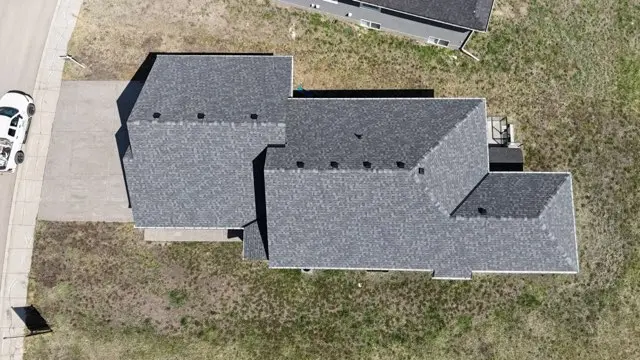 Aerial view of a new grey shingle roof on a home beside an open field