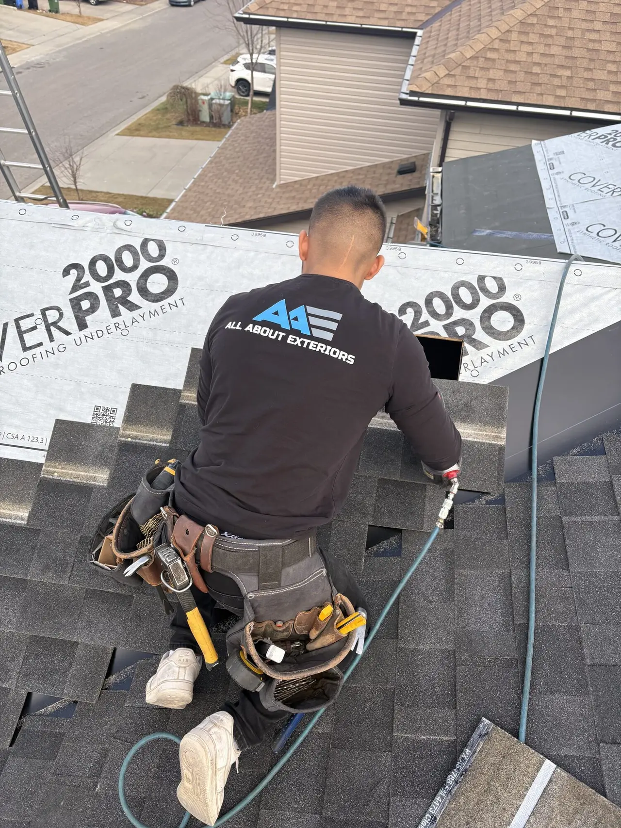 All About Exteriors roofer sealing a roof vent boot on new asphalt shingles, with CoverPro underlayment above
